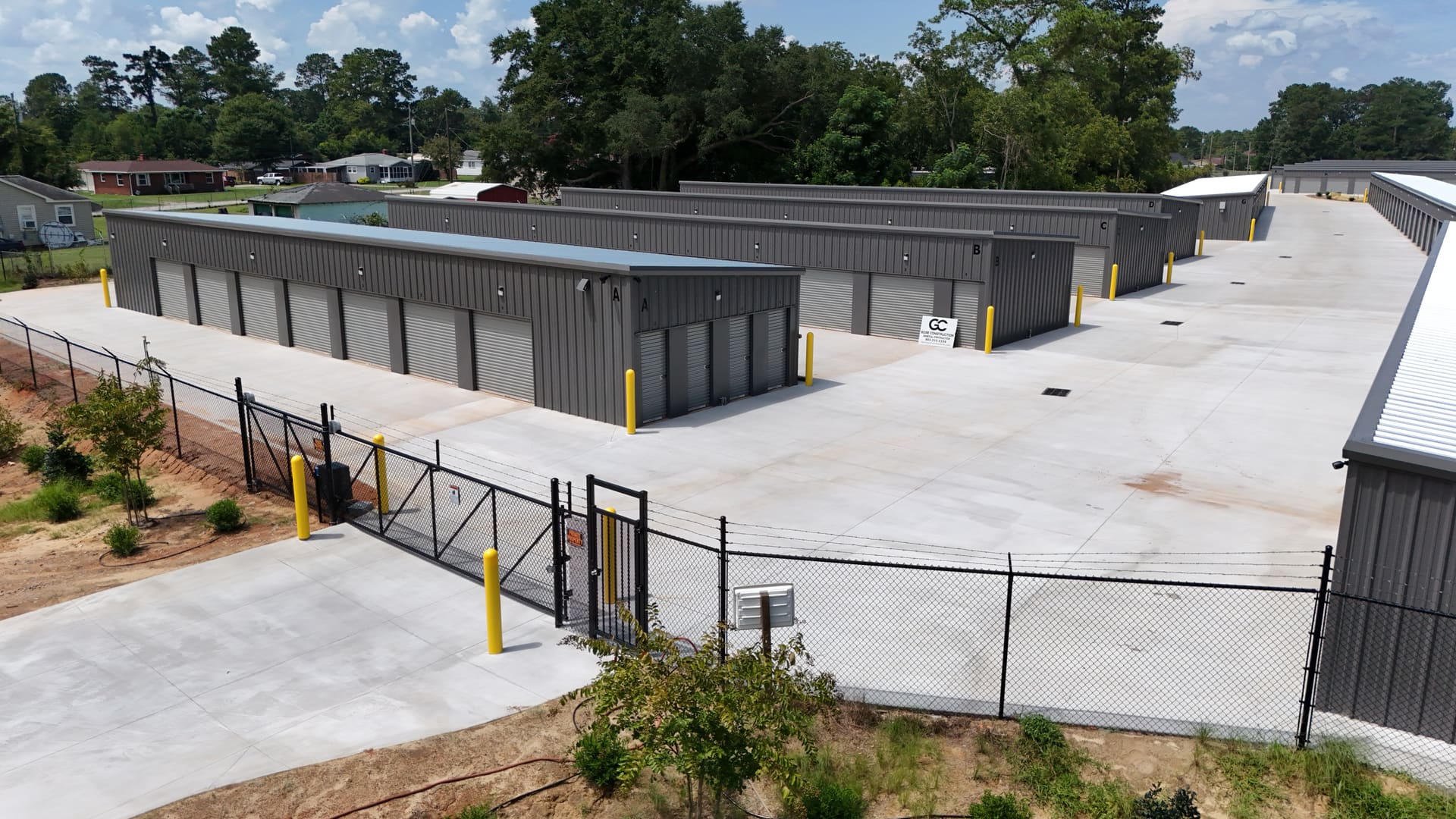 My Storage's black perimeter fencing and gate along the front of the property, with storage buildings and the drive aisle behind it.